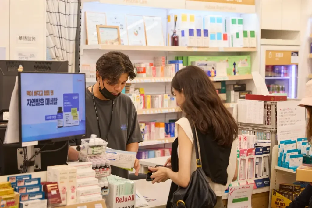 韓国の薬局で薬剤師に再生テープについて相談する様子